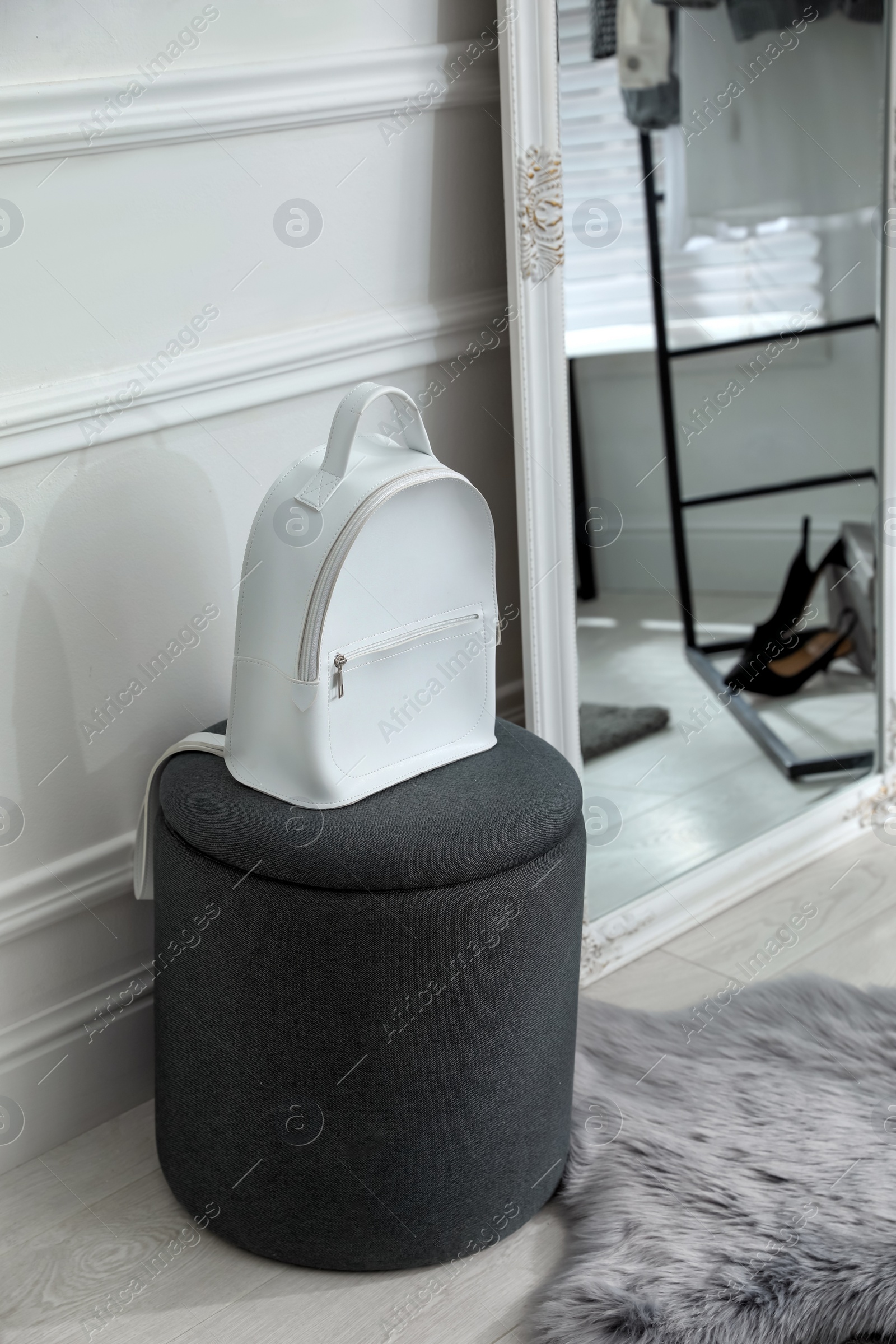 Photo of Stylish white backpack on pouf in dressing room