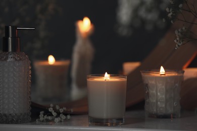 Photo of Beautiful burning candles and gypsophila flowers on white table near mirror indoors.