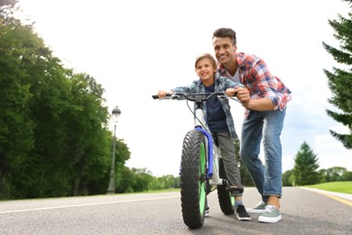 Dad teaching son to ride bicycle outdoors