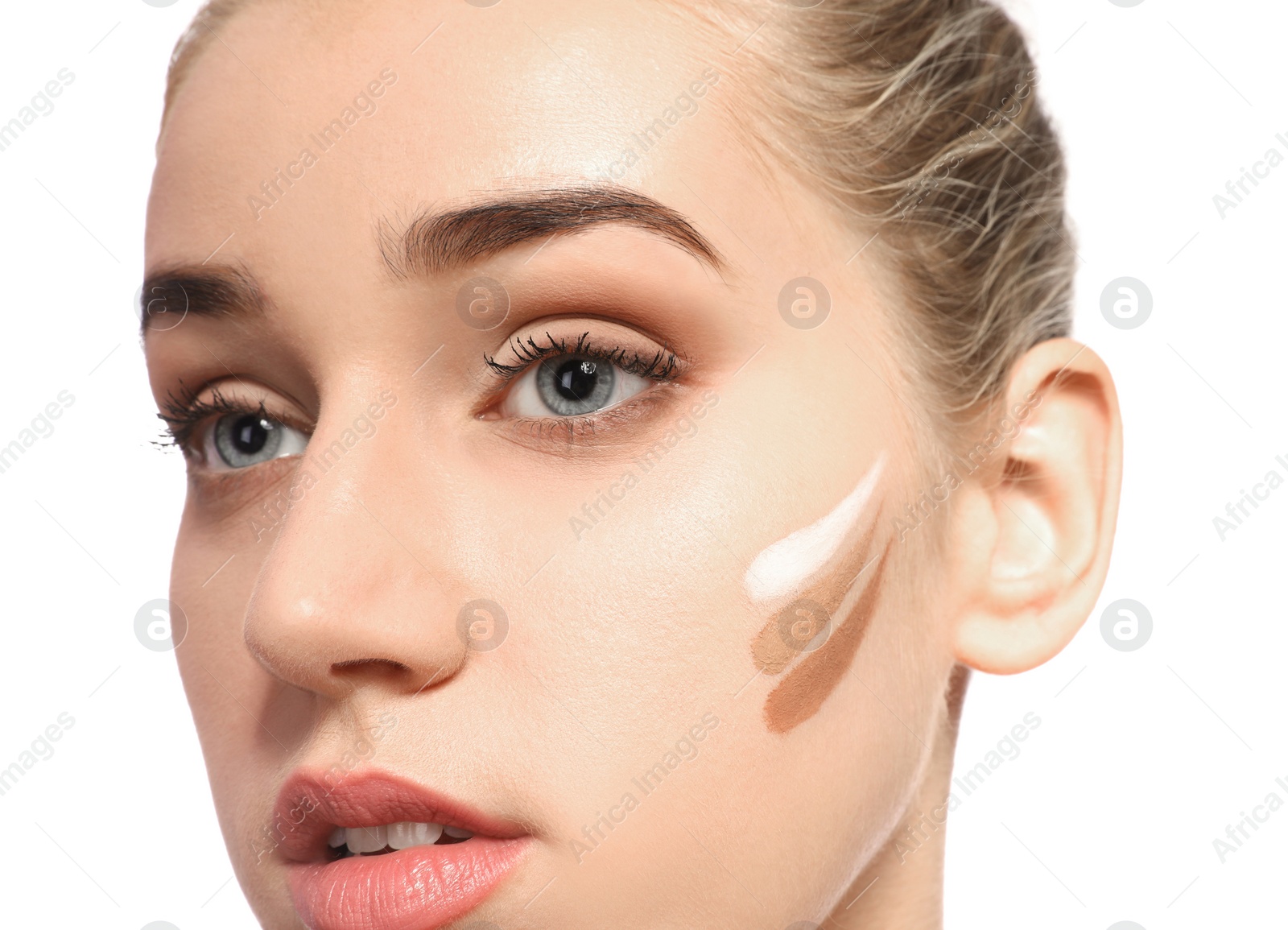 Photo of Young woman with different shades of skin foundation on her face against white background. Professional makeup