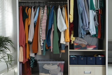 Photo of Wardrobe closet with different stylish clothes and home stuff in room. Fast fashion