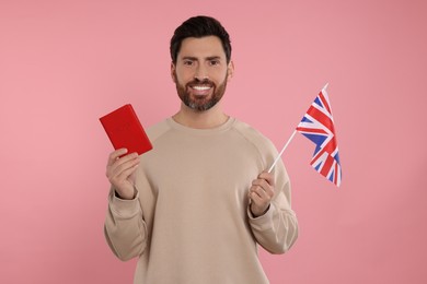 Photo of Immigration. Happy man with passport and flag of United Kingdom on pink background