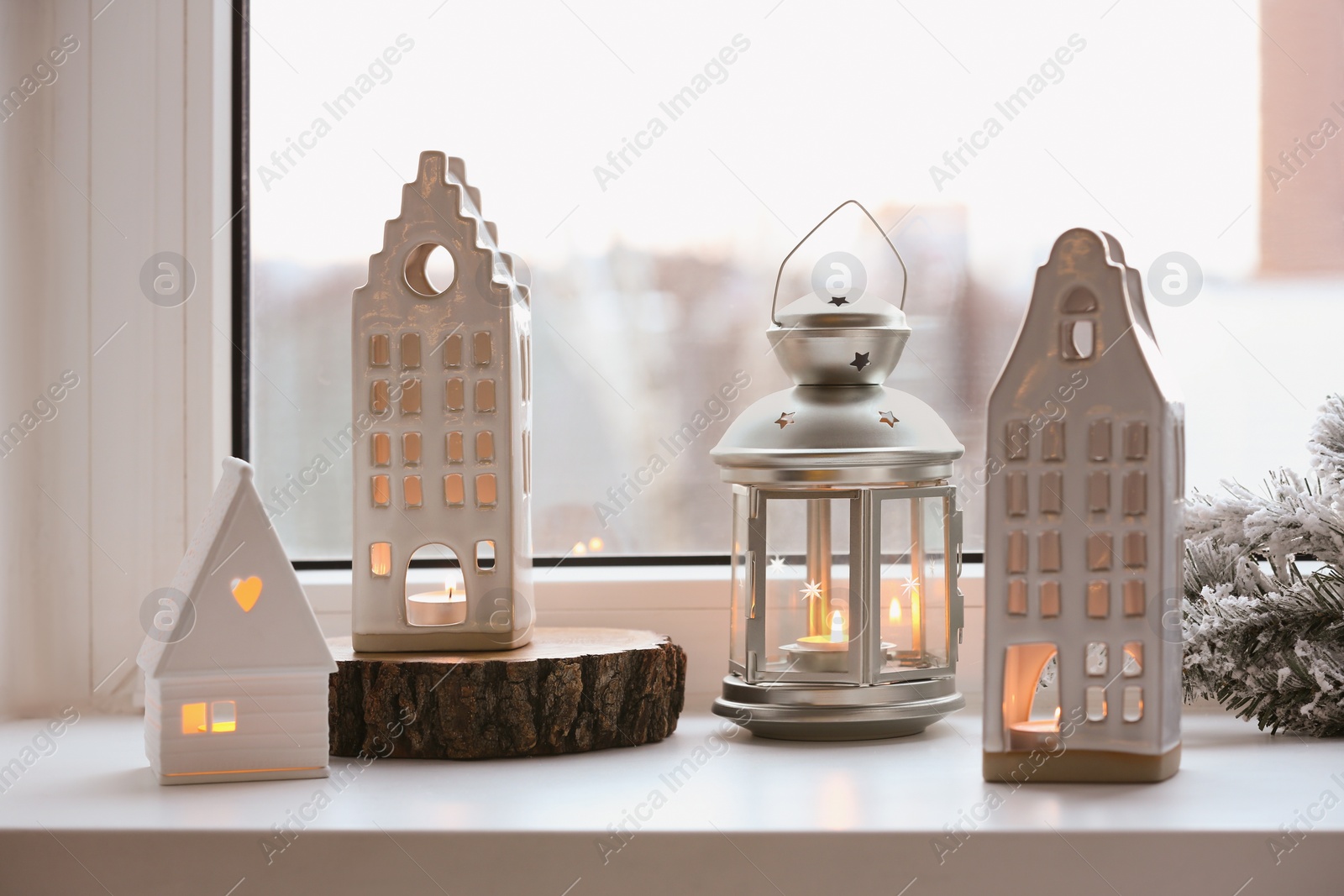 Photo of Beautiful house shaped candle holders and Christmas decor on windowsill indoors