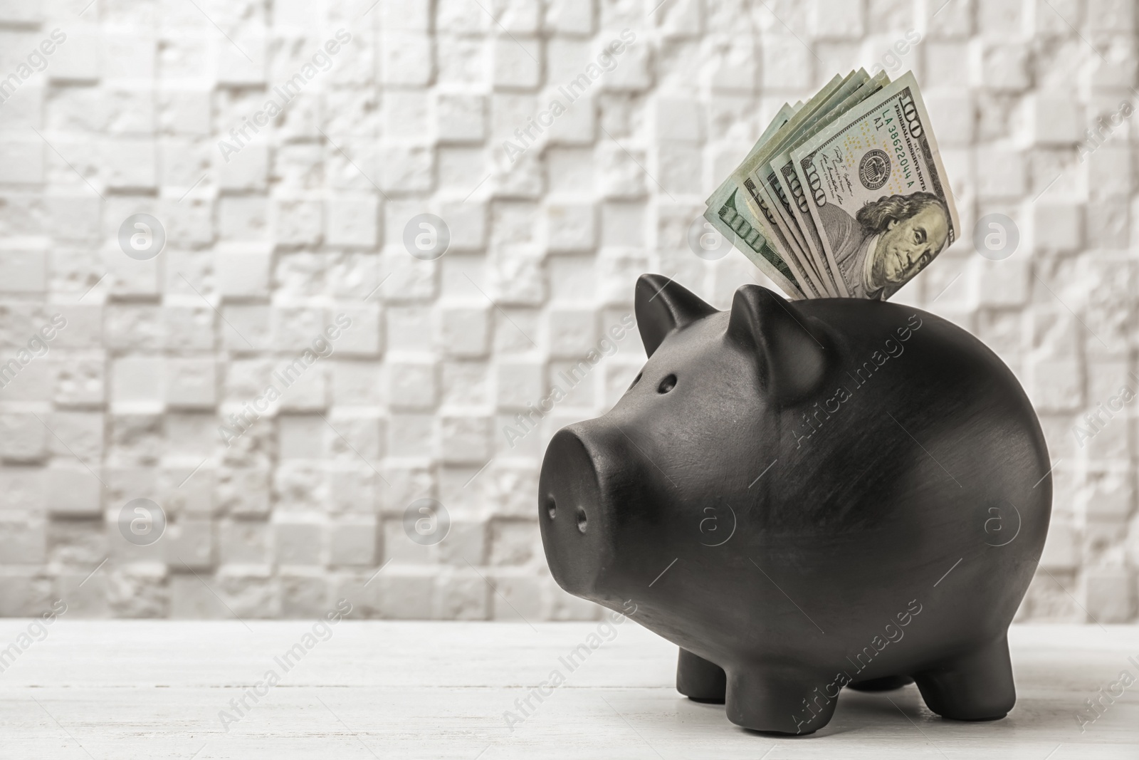 Photo of Black piggy bank with money on table