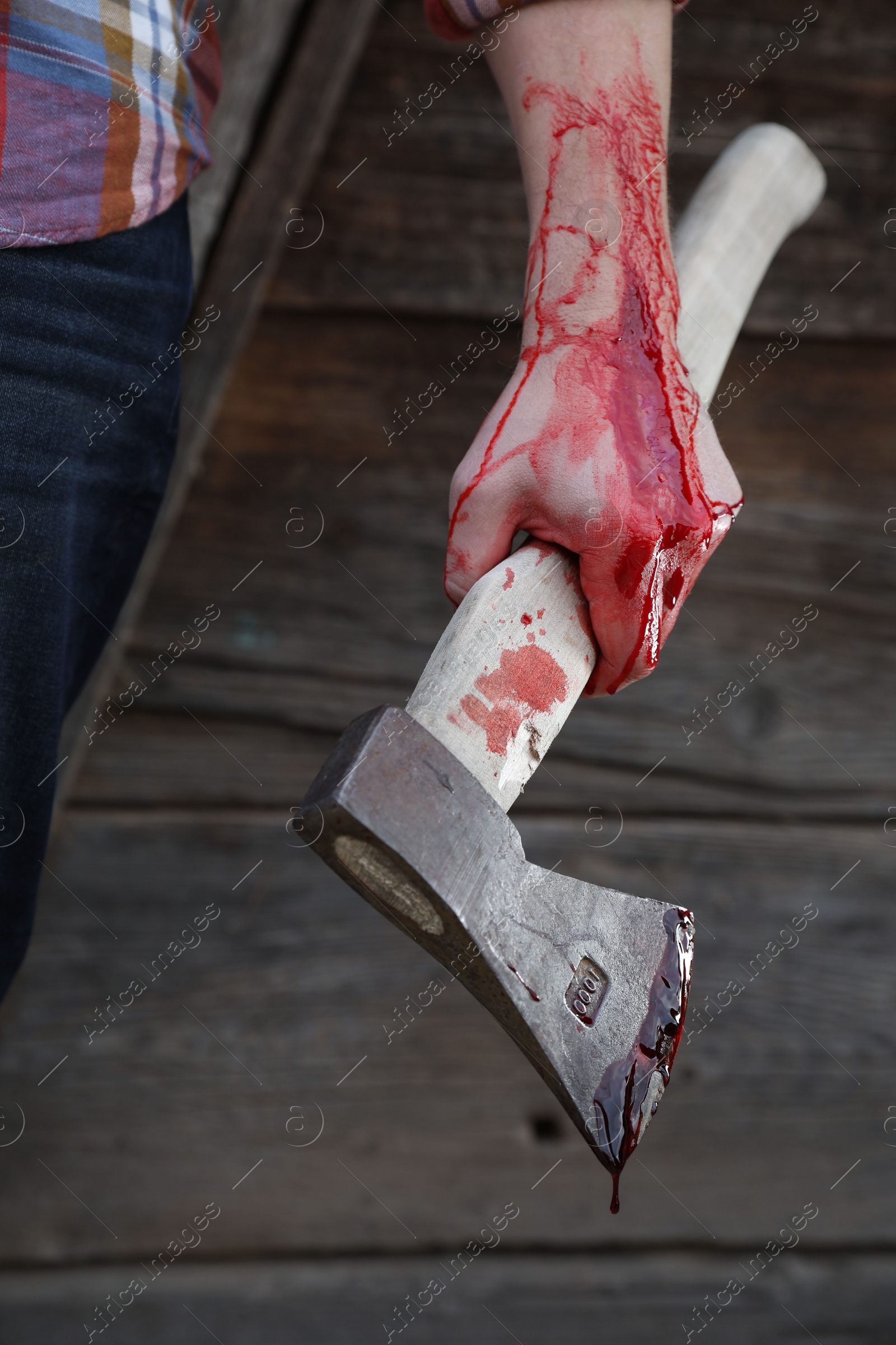 Photo of Man holding bloody axe outdoors, closeup view