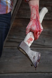 Man holding bloody axe outdoors, closeup view