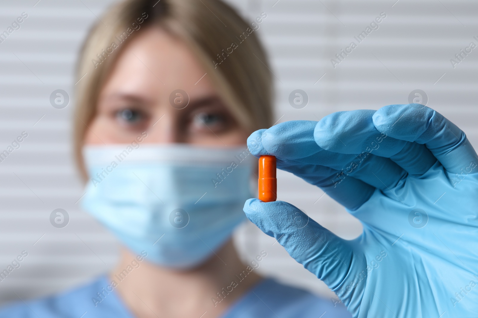 Photo of Doctor holding pill on light background, selective focus