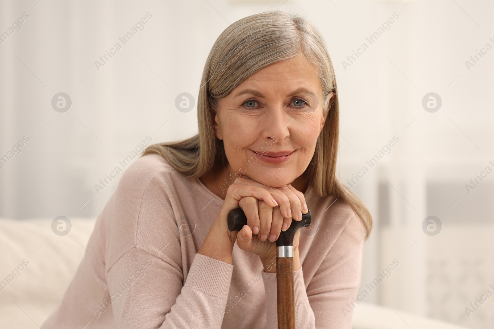 Photo of Beautiful mature woman with walking cane indoors