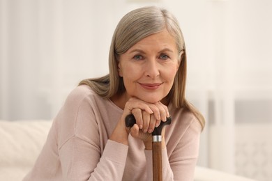 Beautiful mature woman with walking cane indoors