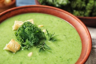 Photo of Tasty kale soup with croutons on table, closeup