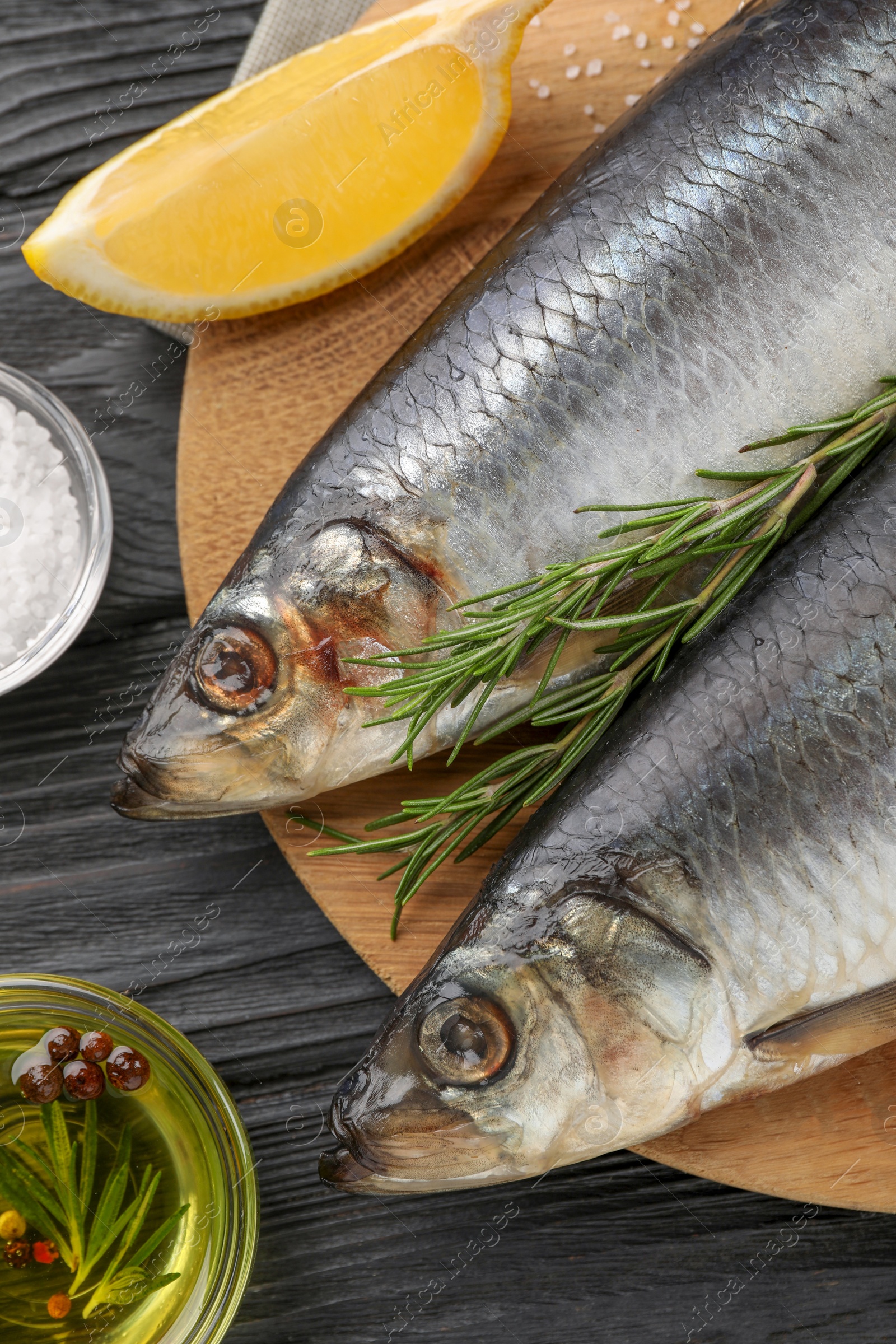 Photo of Delicious salted herrings and ingredients on black wooden table, flat lay