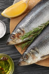 Photo of Delicious salted herrings and ingredients on black wooden table, flat lay