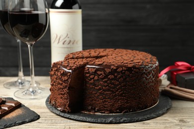 Photo of Delicious chocolate truffle cake and red wine on wooden table