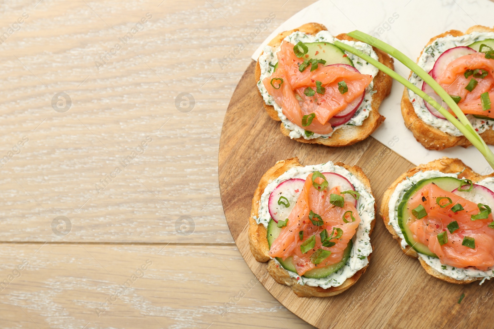 Photo of Tasty canapes with salmon served on wooden table, top view. Space for text