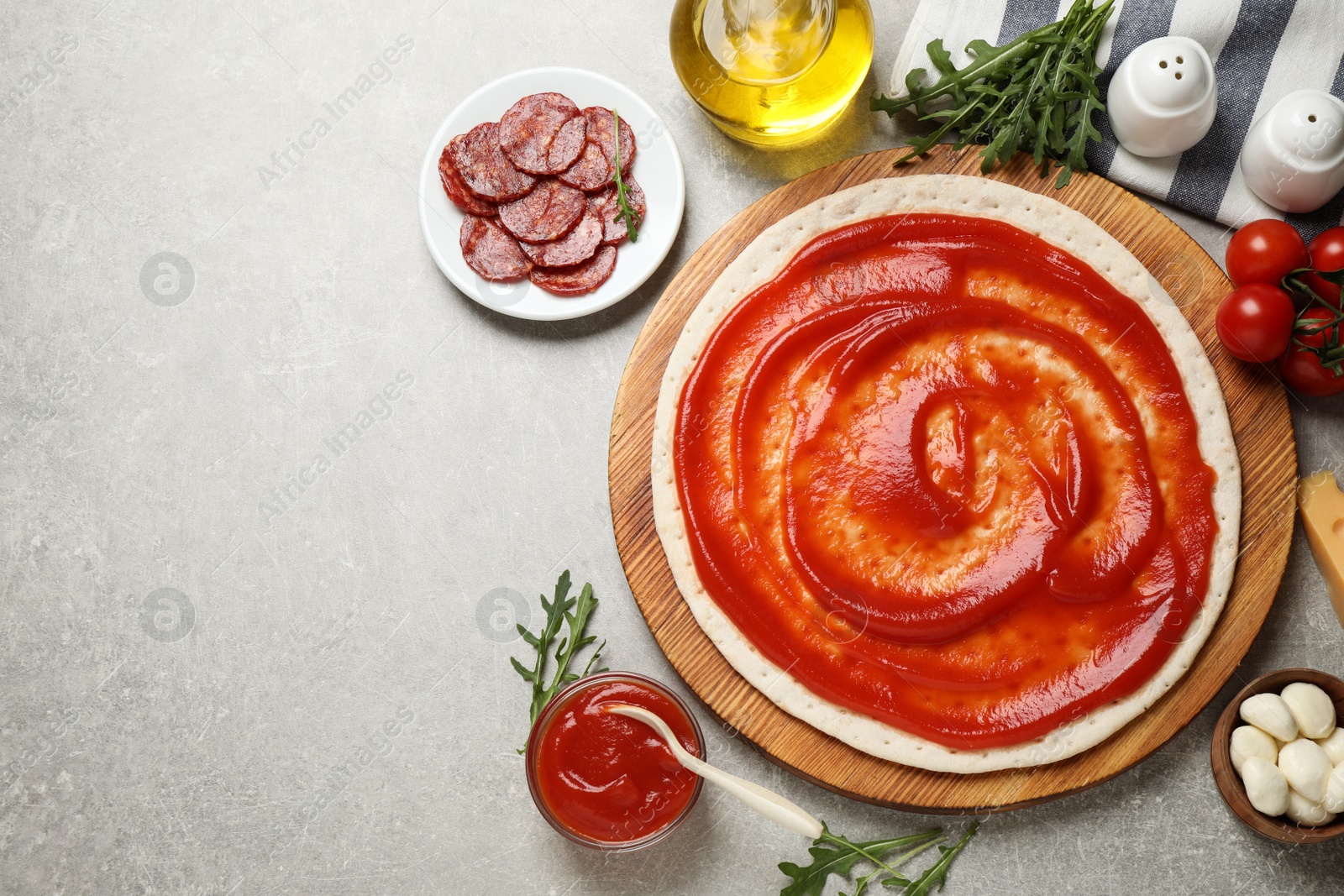 Photo of Flat lay composition with base and ingredients on light grey table, space for text. Pepperoni pizza recipe