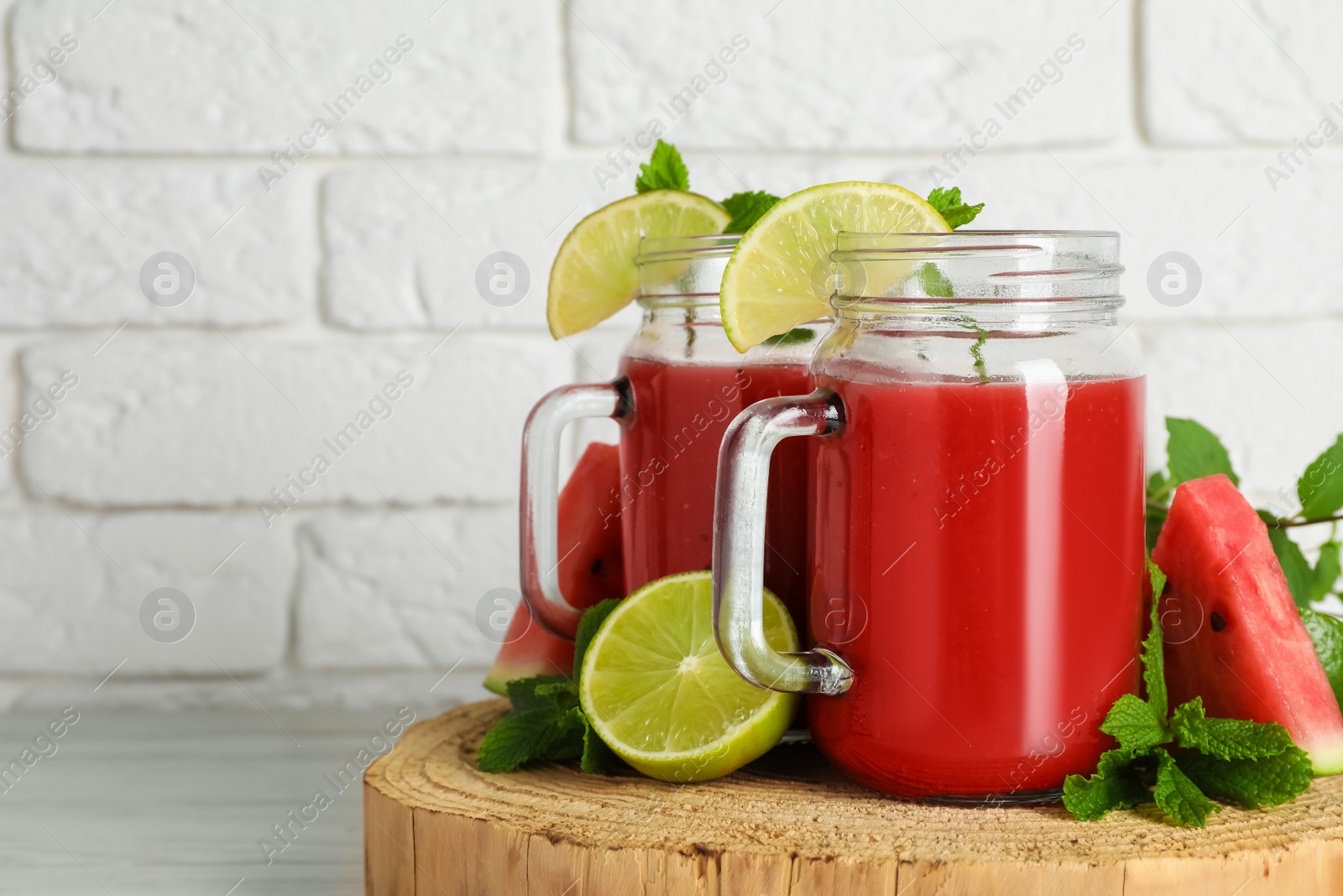 Photo of Tasty summer watermelon drink, limes and mint on white wooden table, space for text