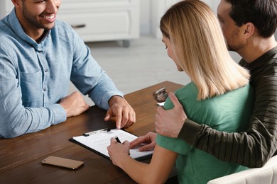 Photo of Notary working with couple at wooden table in office, closeup