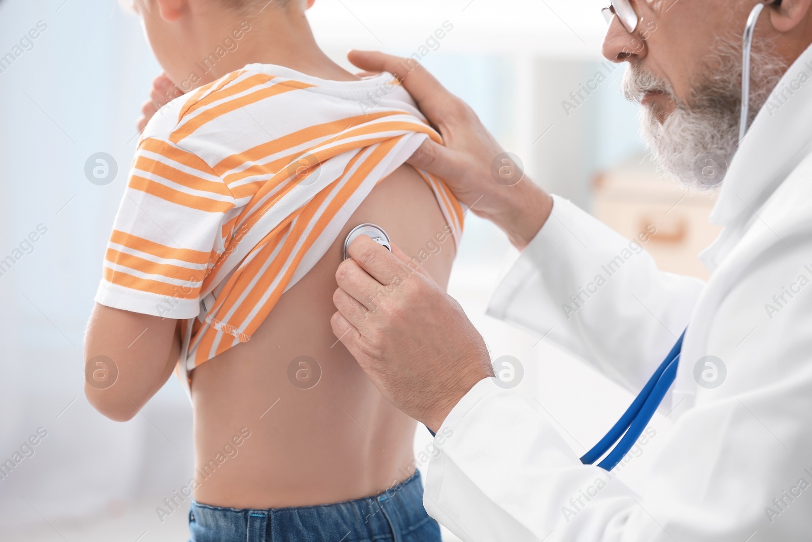 Photo of Doctor examining coughing little boy at clinic