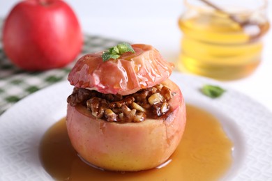 Photo of Tasty baked apple with nuts, honey and mint on table, closeup