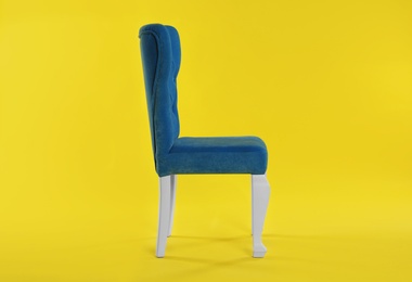 Photo of Stylish blue chair on yellow background. Element of interior design