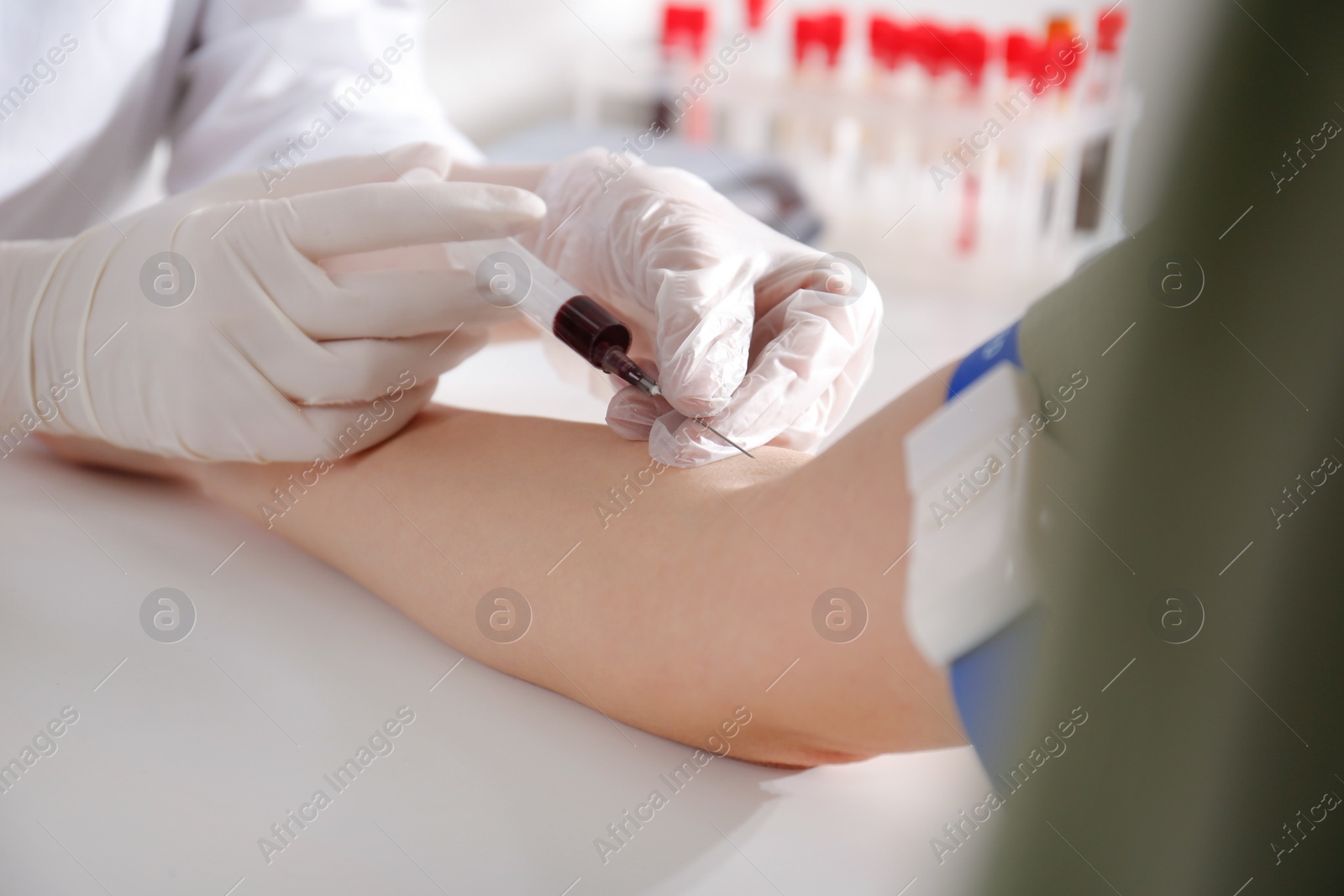 Photo of Nurse drawing blood sample from patient in clinic, closeup