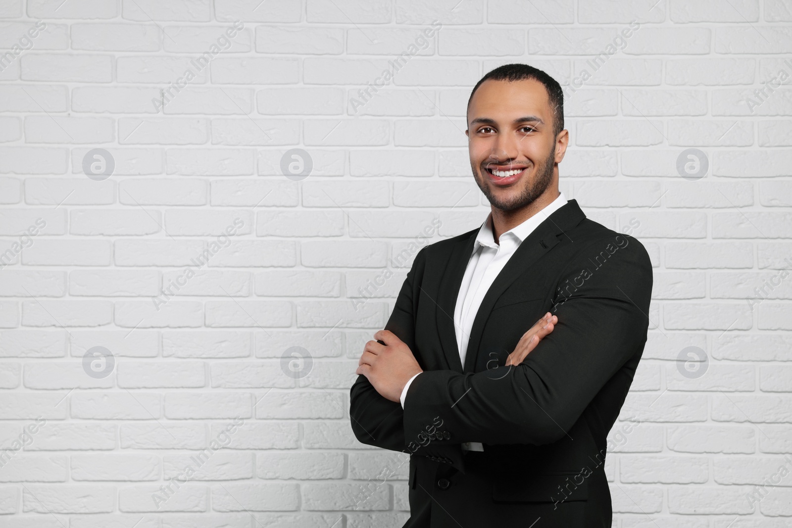 Photo of Young businessman in formal outfit near white brick wall. Space for text