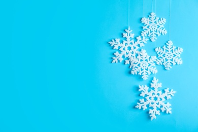 Beautiful decorative snowflakes hanging on light blue background, space for text