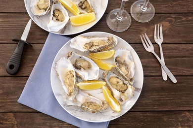 Fresh oysters with cut juicy lemon served on table, flat lay