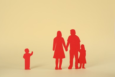 Photo of Paper figures of family and lonely kid on beige background. Child adoption concept