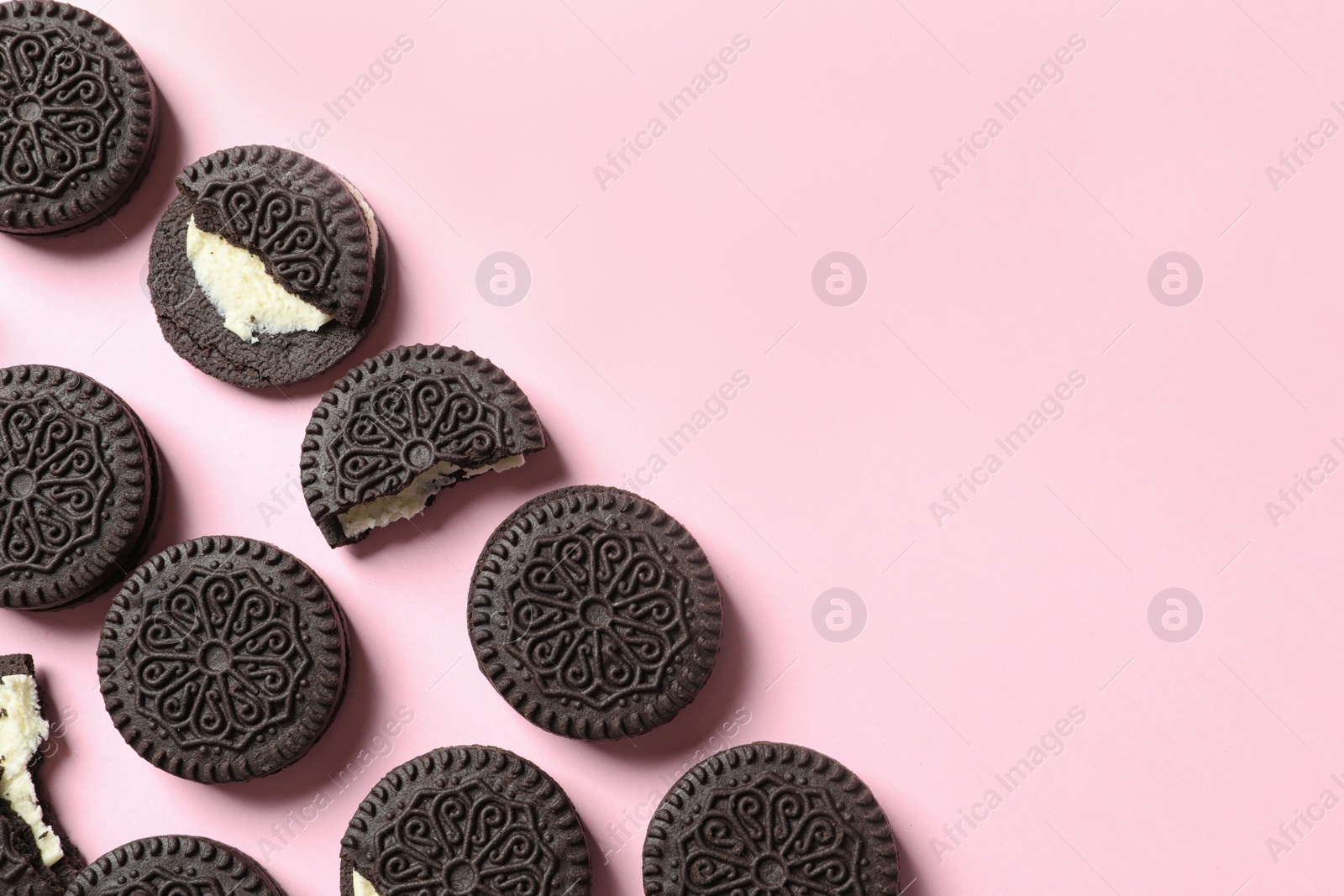 Photo of Tasty chocolate cookies with cream on color background, flat lay. Space for text