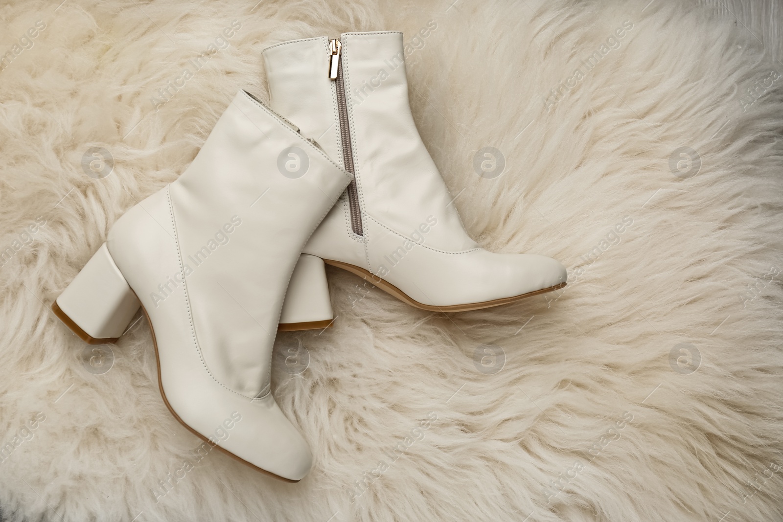 Photo of Pair of stylish leather shoes on faux fur, flat lay