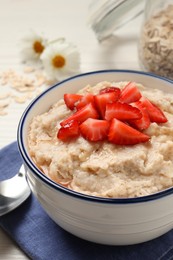 Photo of Tasty oatmeal porridge with strawberries served on table, closeup