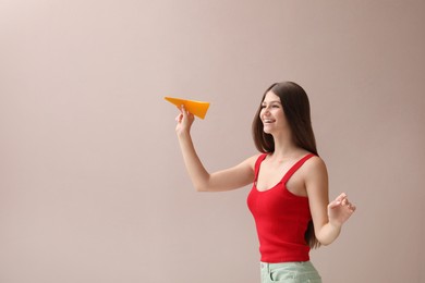 Photo of Beautiful teenage girl with paper plane on beige background. Space for text