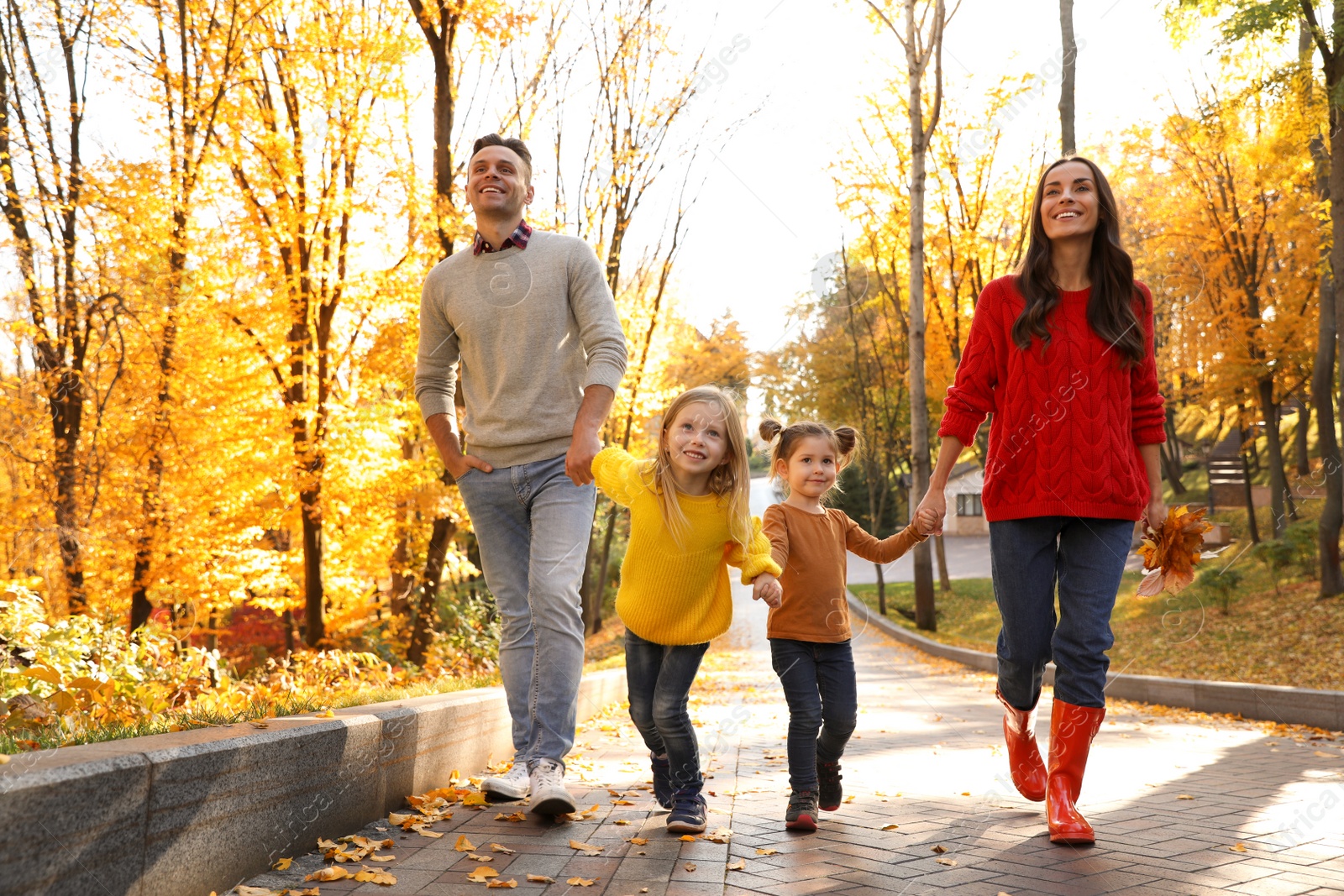 Photo of Happy family with little daughters walking in autumn park