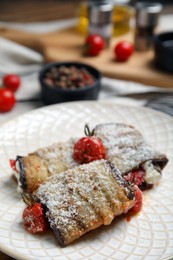 Delicious baked eggplant rolls with tomatoes and cheese on plate, closeup