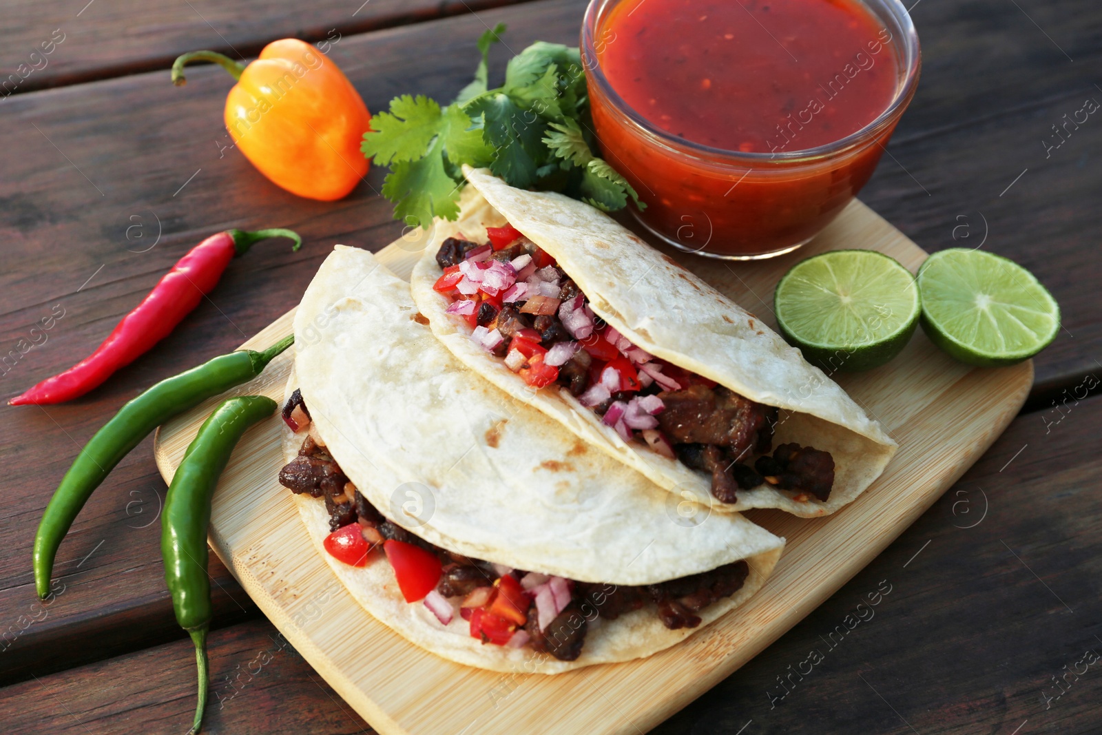 Photo of Delicious tacos with meat, vegetables and sauce on wooden table, above view