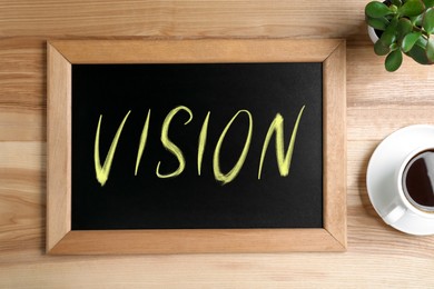 Small chalkboard with word Vision, coffee and plant on wooden table, flat lay