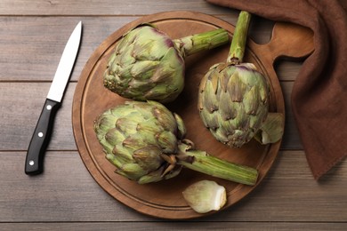 Fresh raw artichokes on wooden table, flat lay