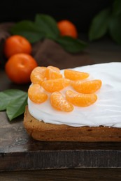 Delicious homemade yogurt cake with tangerines and cream on wooden table, closeup