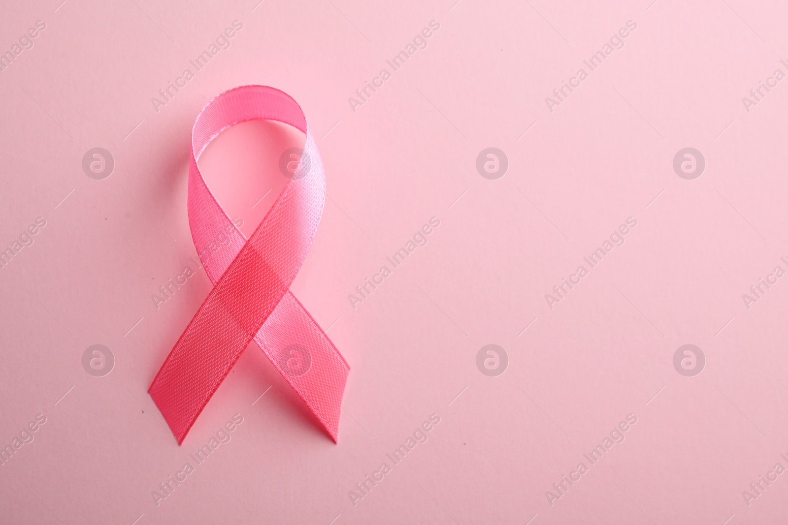 Photo of Pink ribbon on color background, top view with space for text. Breast cancer awareness concept