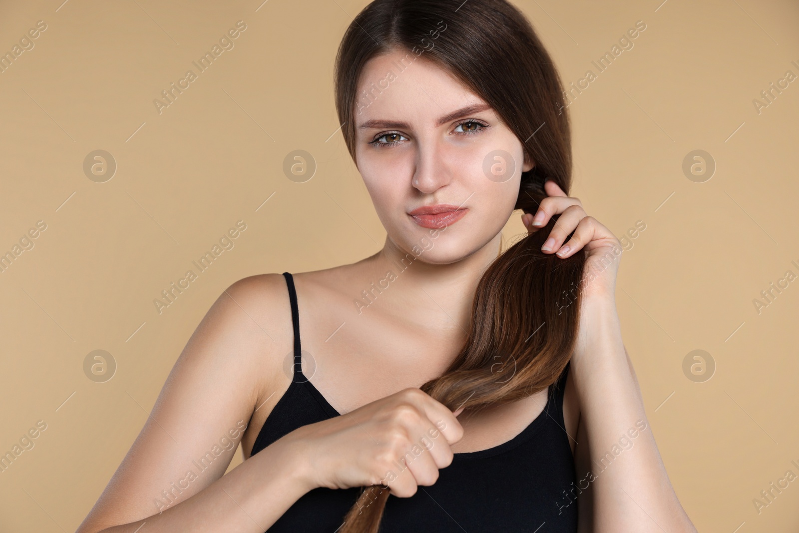 Photo of Young woman with strong healthy hair on beige background