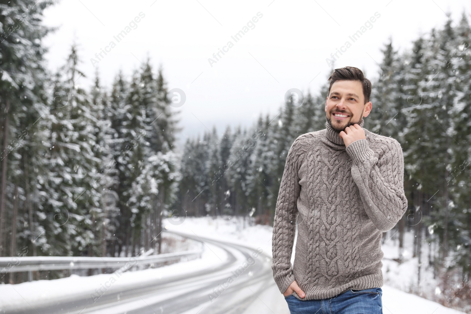 Photo of Man in warm sweater near snowy forest, space for text. Winter vacation