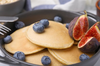 Photo of Tasty oatmeal pancakes with blueberries and fig, closeup