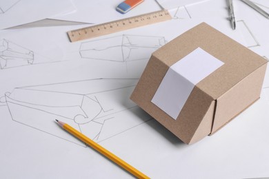 Photo of Creating packaging design. Drawings, box and stationery on table, closeup