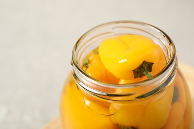 Photo of Glass jar with pickled peppers on grey table, closeup