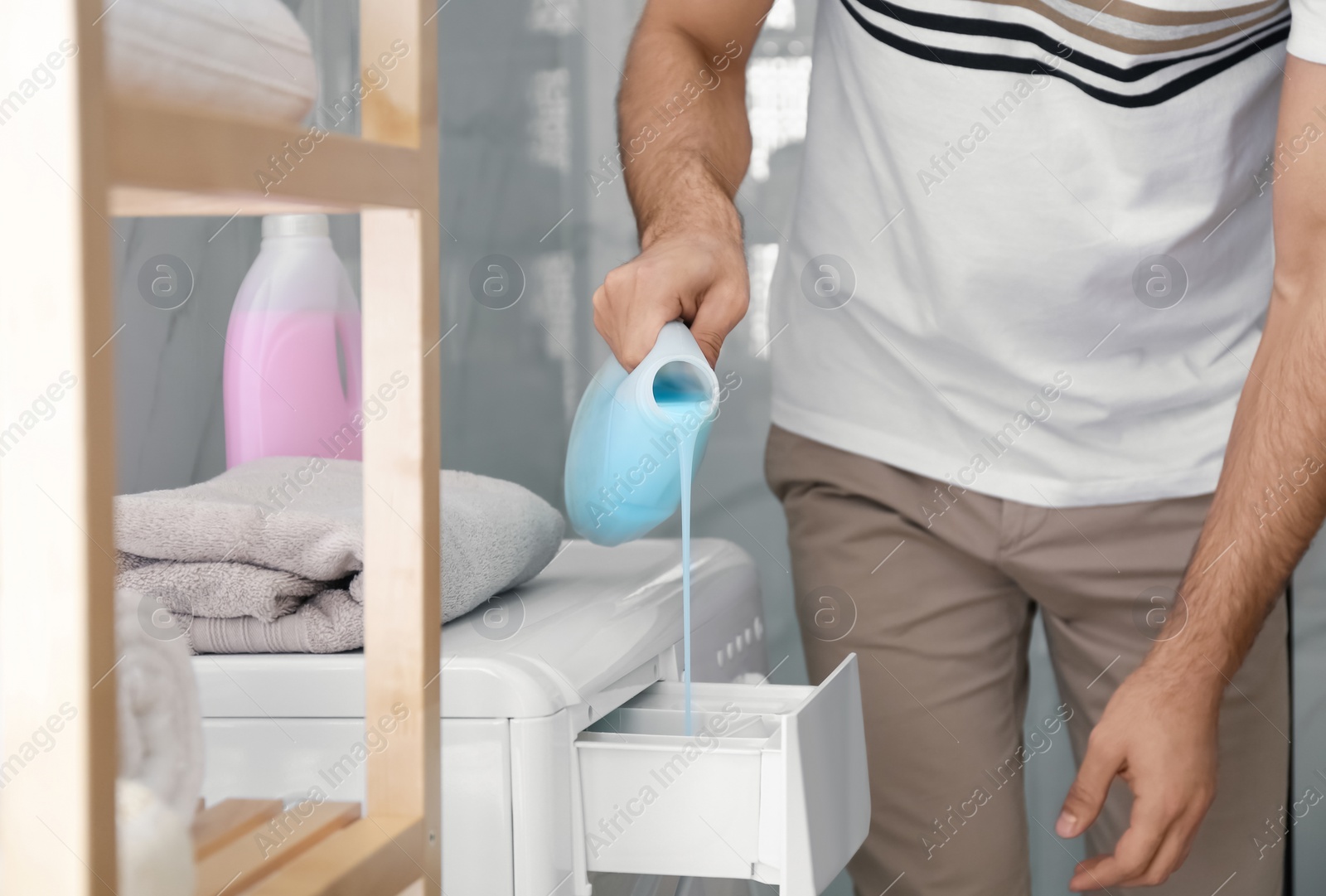 Photo of Man pouring detergent into washing machine drawer in bathroom, closeup. Laundry day