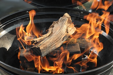 Photo of New modern barbecue grill with burning firewood, closeup