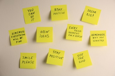 Paper notes with life-affirming phrases on white wall