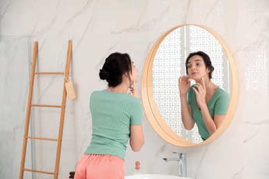 Photo of Beautiful young woman near mirror in bathroom