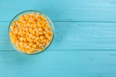 Frozen sweet corn on light blue wooden table, top view with space for text. Vegetable preservation